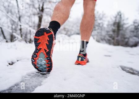 uomo sconosciuto che corre nella neve in inverno primo piano su scarpe da ginnastica Foto Stock
