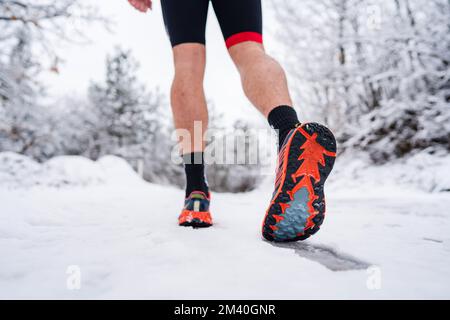 uomo sconosciuto che corre nella neve in inverno primo piano su scarpe da ginnastica Foto Stock