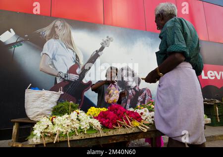 Flowerseller ha allestito il suo negozio di fronte a un poster-concerto Foto Stock