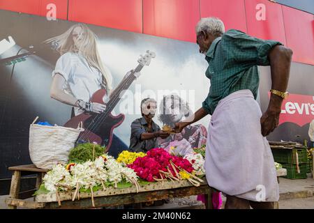 Flowerseller ha allestito il suo negozio di fronte a un poster-concerto Foto Stock