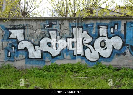 Graffiti specifici dipinti con una lattina di colore bianco e blu con un nome e forme specifici su una parete di cemento. Foto Stock