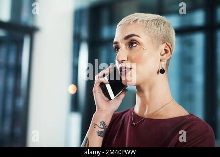 Sigillare l'affare sopra il telefono. una giovane donna d'affari attraente che si alza da sola nel suo ufficio e che parla sul suo cellulare. Foto Stock