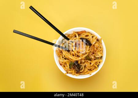 Spaghetti con pollo, carne, fagioli, carote di funghi e verdure, colore giallo brillante, vista dall'alto Foto Stock