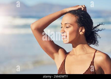 Sabbia tra le dita dei piedi e l'aria da spiaggia contro il mio viso. una bella giovane donna che trascorre la giornata in spiaggia. Foto Stock