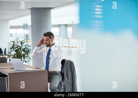 I messaggi istantanei iniziano a sfracearsi... un giovane uomo d'affari che guarda scioccato mentre lavora su un notebook in ufficio. Foto Stock