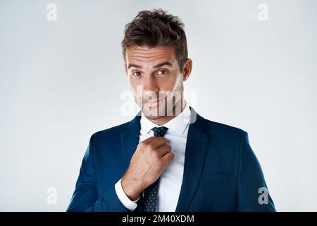Un bel mister. Ritratto di un giovane uomo d'affari sicuro che indossa una tuta in piedi su uno sfondo grigio. Foto Stock