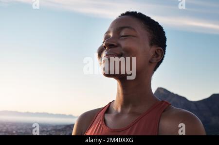 Fitness, calma e respiro di donna nera all'aperto nella natura, montagne e cielo blu sfondo per yoga benessere, meditazione e zen energia. Faccia di Foto Stock