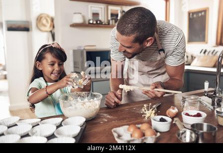 Le famiglie sono come un fudge per lo più dolce, con qualche noce. un padre insegna a sua figlia come cuocere in cucina a casa. Foto Stock