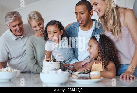 Grande famiglia, torta di compleanno e candele soffiate per un desiderio a casa con genitori, nonni e bambini insieme per una celebrazione. Uomini, donne e. Foto Stock