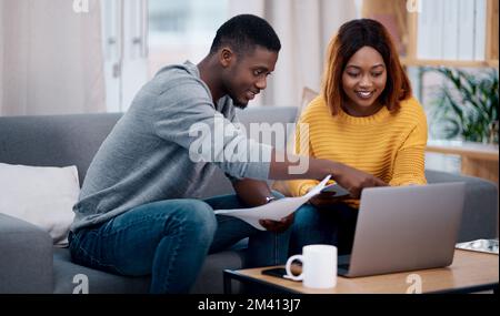 Risparmiiamo tempo e denaro facendo le cose online. una coppia che passa attraverso alcuni documenti mentre si siede con un notebook. Foto Stock