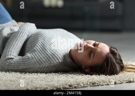 Triste adolescente steso sul pavimento a casa di notte Foto Stock