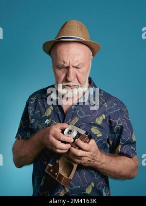 Un fotografo anziano regola la fotocamera Foto Stock