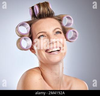 Capelli, arricciacapelli e pensare con una modella donna in studio su uno sfondo grigio con rulli per acconciatura. Cura dei capelli, curling e idea con un attraente Foto Stock