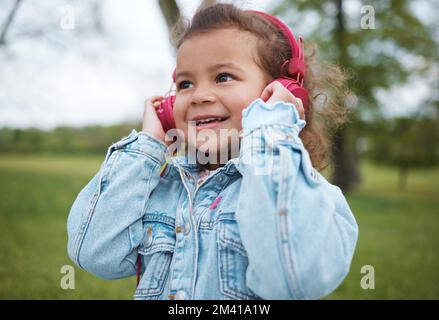 Musica, sorriso e bambino in un parco con cuffie, libertà radio e audio in streaming in Portogallo. Podcast, felice e volto di un bambino ragazzo che ascolta un Foto Stock