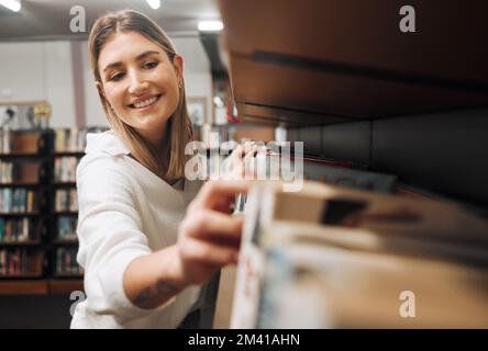 Libri di biblioteca, studenti e donne che confezionano libri di testo in un negozio di libri per l'istruzione, l'università e l'apprendimento. Scuola, università e felice laureato in cerca di Foto Stock