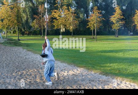 Giovane ragazza in sella a un bungee appeso sul parco giochi. Autunno all'aperto Foto Stock