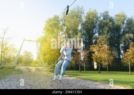 Divertimento autunnale. Ragazza giovane in sella all'aperto un bungee appeso sul parco giochi Foto Stock