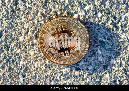 Moneta bitcoin d'oro posta su fondo di pietra. Criptovaluta virtuale nel mondo reale Foto Stock