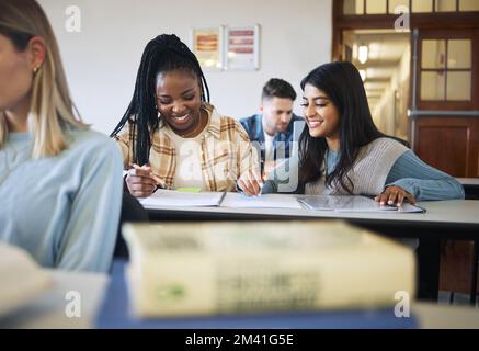 Studenti, donne e studiare in classe, felice e conversazione per prepararsi per l'esame, il successo e l'apprendimento insieme. Giovani femmine, ragazze e. Foto Stock