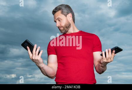 scioccato uomo blogger tipo messaggio di telefono indossare tshirt rossa. Foto Stock