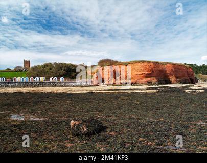La roccia di arenaria rossa Permian affioramento di Hollicombe Head alla fine della parata marina e le sue capanne spiaggia, Preston Sands, Paignton, Torbay, South Devon, Foto Stock