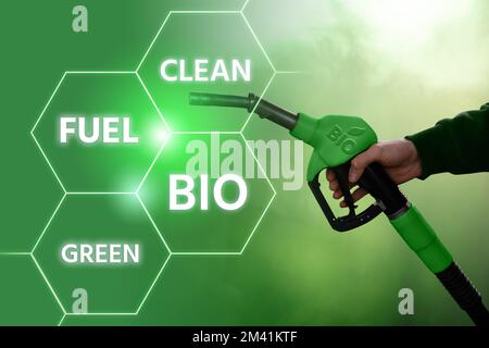 Mano con ugello del carburante con iscrizione BIO. Concetto di decarbonizzazione del carburante biologico a emissioni di carbonio neutre Foto Stock