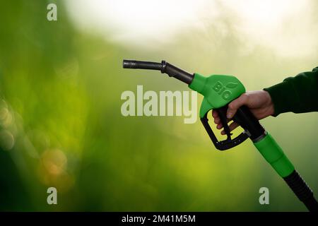 Mano con ugello del carburante con iscrizione BIO. Concetto di decarbonizzazione del carburante biologico a emissioni di carbonio neutre Foto Stock