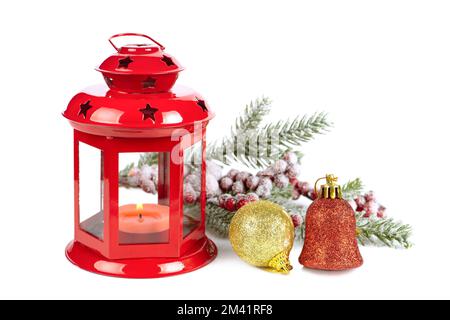 Lanterna rossa bruciante con rametto di abete innevato decorato e decorazioni natalizie isolate su sfondo bianco Foto Stock