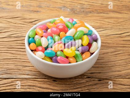 Fagioli di gelatina colorati in una ciotola sopra il tavolo di legno. Foto Stock