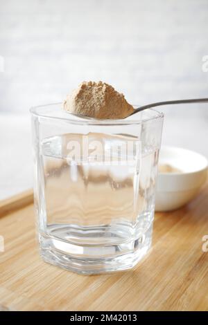 mescolando i fiocchi di lievito dei birrifici in un bicchiere d'acqua Foto Stock