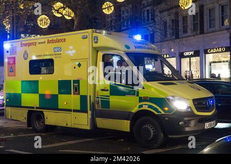 Londra, Regno Unito, 17 dicembre 2022: Un'ambulanza di emergenza lo fa attraversare il traffico pesante a Knightsbridge, con le luci di Natale sullo sfondo. In Inghilterra e Galles i conducenti di ambulanze dei sindacati GMB, Unison e Unite dovranno scioperarsi il 21 dicembre in una disputa sulla retribuzione. Anna Watson/Alamy Live News Foto Stock