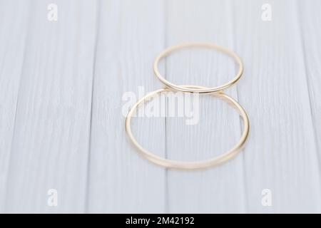 Due anelli d'oro di nozze si trovano su un tavolo di legno bianco. rendering 3d.. Foto Stock