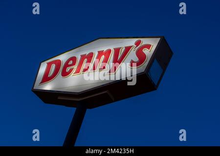 Viene mostrato un cartello illuminato con il palo di Denny con il cielo blu scuro nella notte. Foto Stock