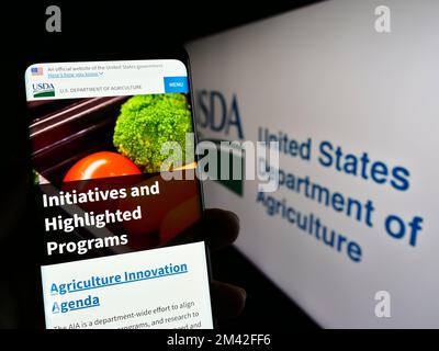 Persona che tiene il cellulare con pagina web del Ministero dell'Agricoltura degli Stati Uniti (USDA) sullo schermo con il logo. Messa a fuoco al centro del display del telefono. Foto Stock