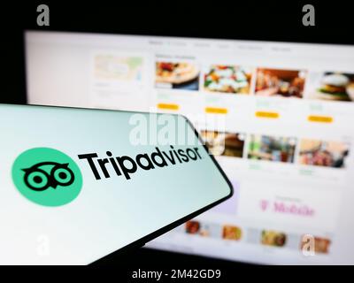 Telefono cellulare con il logo della società di viaggi americana TripAdvisor Inc. Sullo schermo di fronte al sito web aziendale. Messa a fuoco al centro a sinistra del display del telefono. Foto Stock