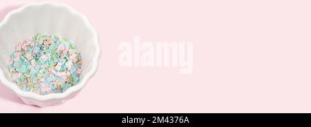 Una ciotola piena di microsplastici su fondo rosa. Impatto della micro plastica nella catena alimentare. Il concetto di inquinamento plastico. Composizione di una ciotola Foto Stock