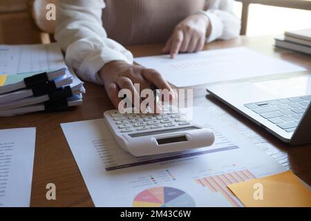 Immagine ritagliata di una donna d'affari professionale, di un imprenditore o di un commercialista che lavora su una documentazione finanziaria alla sua scrivania, utilizzando una calcolatrice, un notebook Foto Stock