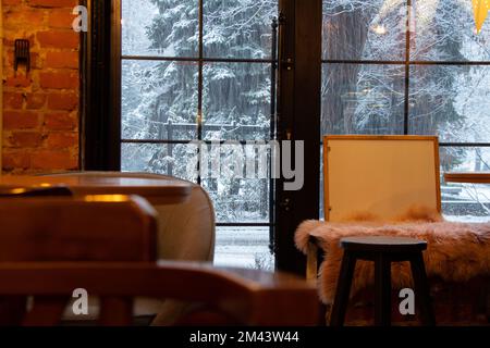 Cafe con vista sulla neve dalla finestra in Ucraina, l'interno del cafè con mobili in legno Foto Stock