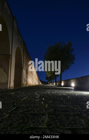 Una strada stretta lungo le mura del castello di Baia in una foto notturna, Italia. Foto Stock