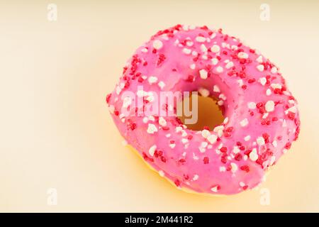 Ciambella rosa dolce con spolverini multicolore su fondo giallo. Dessert dolce colorato Foto Stock