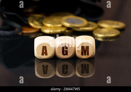 Business e concetto di economia. Su una superficie nera riflettente sono le monete e i cubi di legno con l'iscrizione - AGM Foto Stock