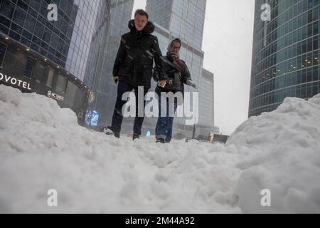 Mosca, Russia. 18th dicembre 2022. Le persone camminano sul Centro Affari Internazionale di Mosca 'Mosca-Città sullo sfondo dei grattacieli durante anormali nevicate nel centro di Mosca, Russia Foto Stock