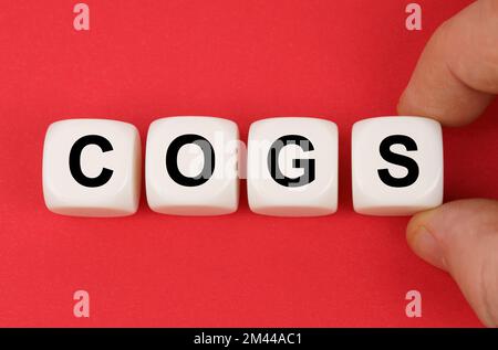 Affari e finanza. Sulla superficie rossa, cubetti bianchi con l'iscrizione - COGS Foto Stock