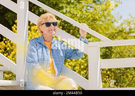 Donna matura attraente viaggiatore seduto da solo sulla terrazza del caffè sulla spiaggia Foto Stock