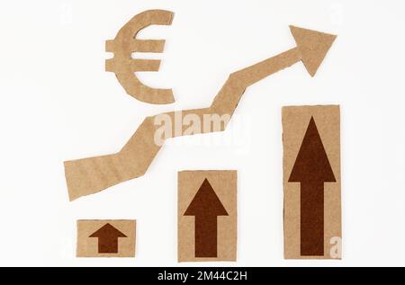 Il concetto di crescita economica. Su una superficie bianca, un grafico con frecce verso l'alto e un simbolo dell'euro. Simbolo, freccia e grafico sono realizzati in cartone Foto Stock