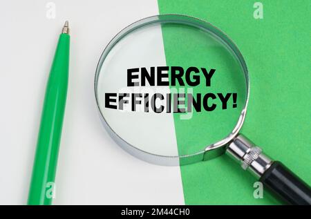 Concetto ecologico. Su uno sfondo bianco-verde si trova una penna e una lente d'ingrandimento, all'interno della quale si trova l'iscrizione - efficienza energetica Foto Stock