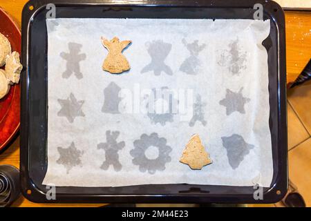 Figure di pan di zenzero natalizio cotte su una teglia da forno. Due rimasero, il resto rimosso. Foto Stock