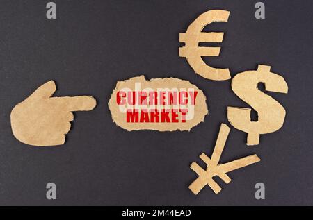 Economia e finanza. Su una superficie nera, una figura di una mano, simboli di denaro e cartone strappato con l'iscrizione - mercato valutario Foto Stock