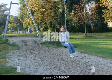 Divertimento all'aperto giovane ragazza in sella a un bungee appeso sul parco giochi Foto Stock