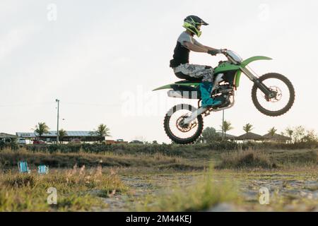 Un biker uomo con un casco in moto e facendo la grande esperienza in campo rurale Foto Stock